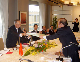 武藤委員長(左)が大使に記念品を贈る